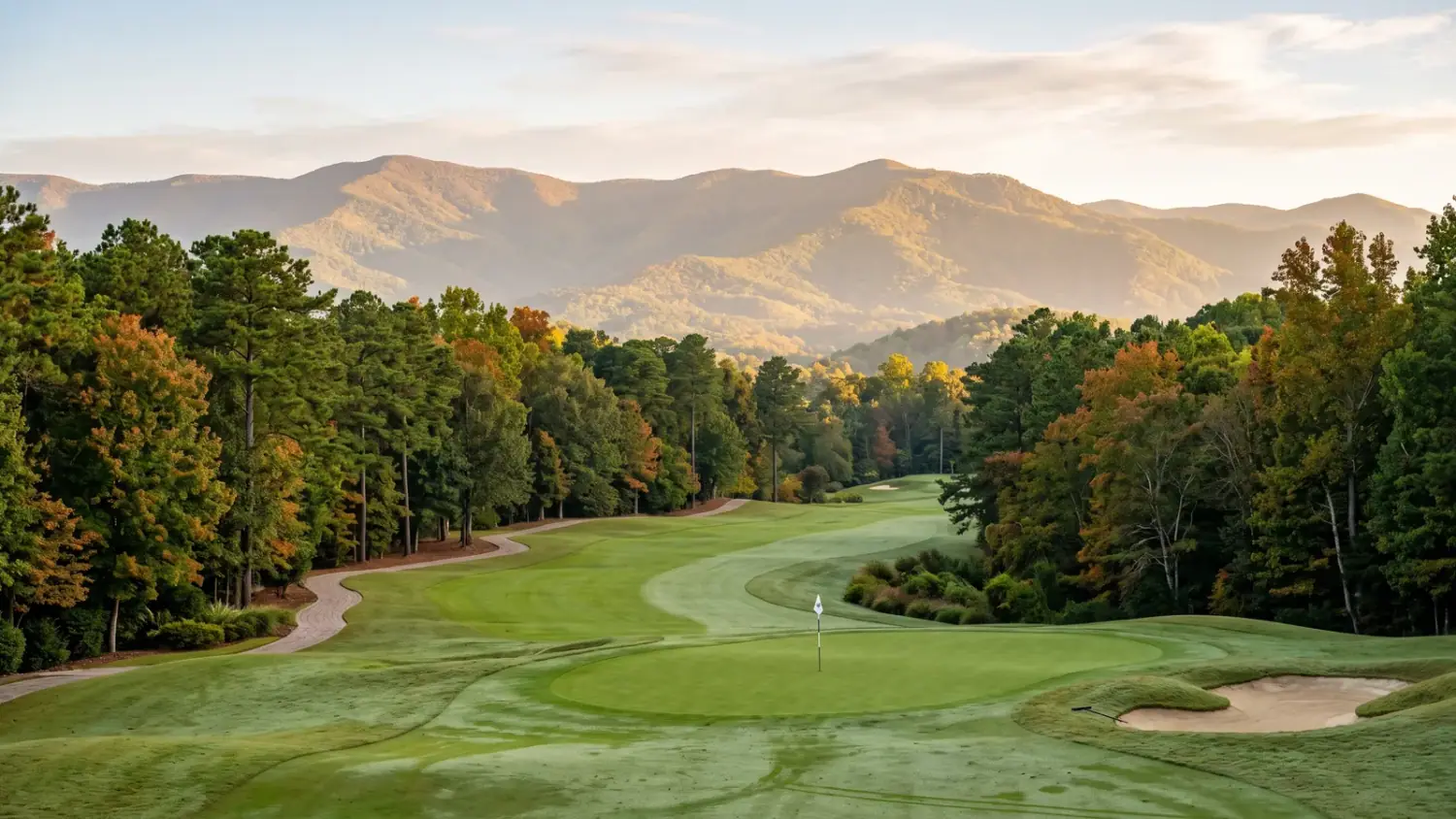 Manicured Chestatee golf-community fairway at soft mid-morning light with mature Southern hardwoods and a distant North Georgia mountain ridge